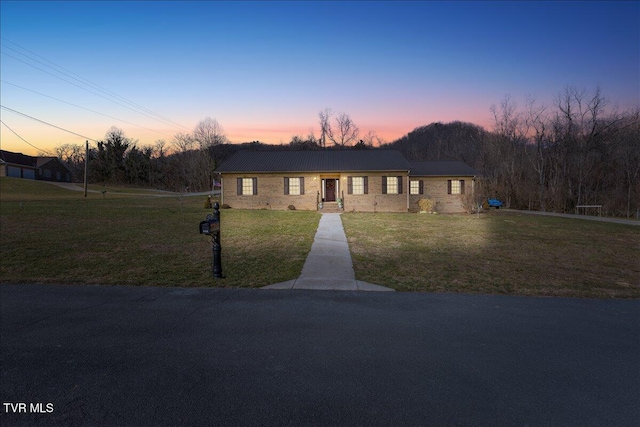 single story home featuring metal roof, a front lawn, and brick siding