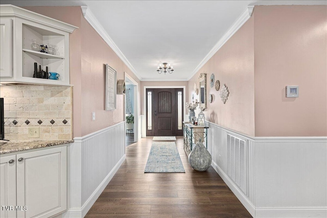 entryway featuring crown molding, visible vents, dark wood-type flooring, and wainscoting