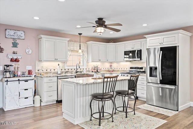 kitchen featuring appliances with stainless steel finishes, light wood-type flooring, a kitchen island, and a kitchen breakfast bar