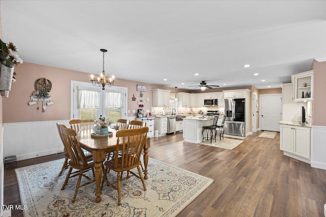 dining space featuring recessed lighting, wainscoting, wood finished floors, and a notable chandelier