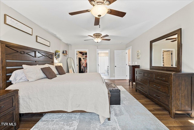 bedroom with ensuite bathroom, ceiling fan, a spacious closet, a closet, and dark wood finished floors