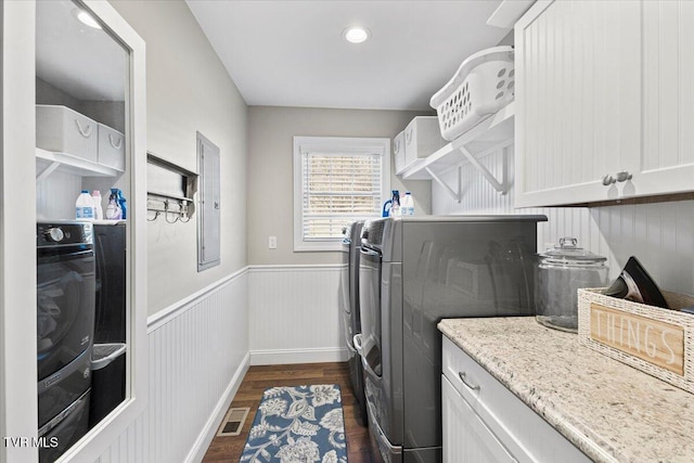 laundry area featuring a wainscoted wall, separate washer and dryer, dark wood-style flooring, visible vents, and electric panel