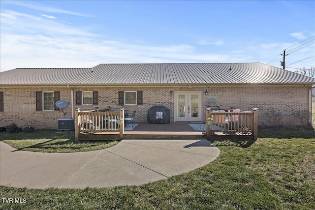 back of property featuring brick siding, metal roof, and french doors