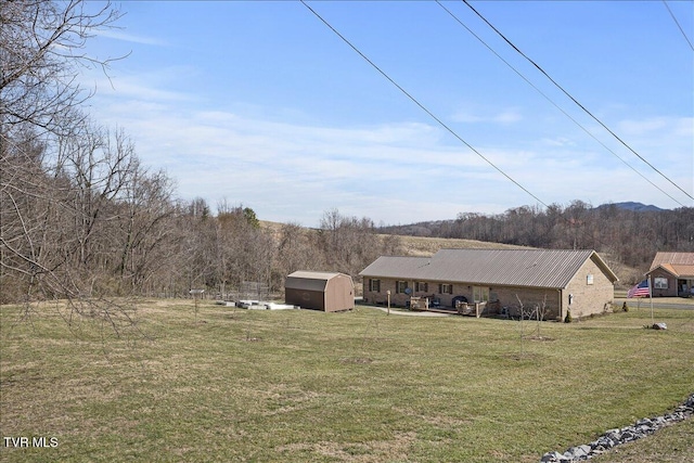 exterior space featuring a shed, a wooded view, and an outbuilding