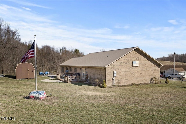 exterior space with a storage shed, brick siding, a lawn, and an outbuilding