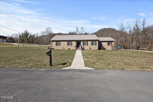 view of front of home with metal roof and a front lawn