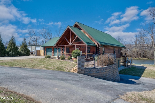 cabin with a garage, metal roof, a porch, and log exterior