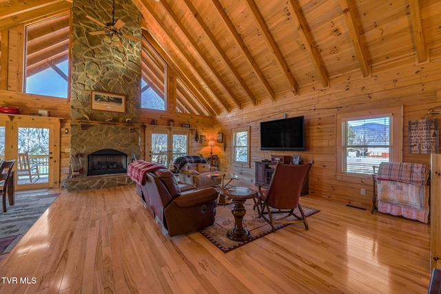 living area featuring wooden ceiling, beamed ceiling, wood finished floors, wood walls, and a fireplace