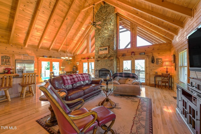 living area featuring wood ceiling, a stone fireplace, light wood-type flooring, wood walls, and a notable chandelier