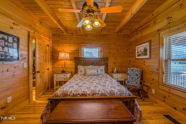 bedroom with multiple windows, beamed ceiling, and wooden walls