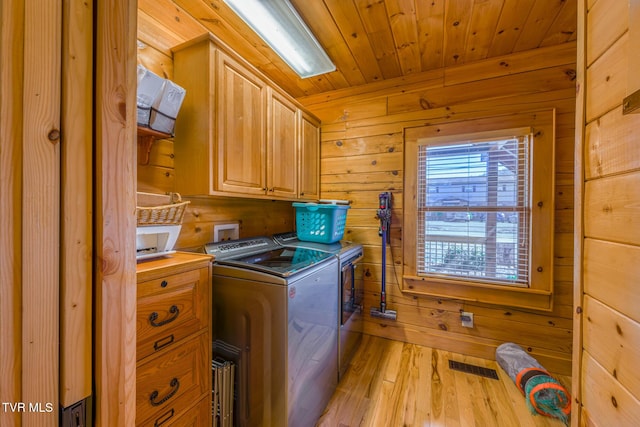 laundry area featuring wooden ceiling, cabinet space, wood walls, and separate washer and dryer