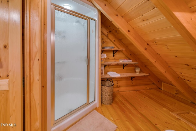 bathroom with hardwood / wood-style floors, a shower stall, wood ceiling, and wooden walls