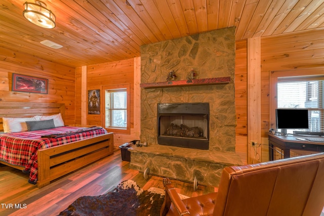 bedroom featuring wood walls, wood ceiling, a fireplace, and wood finished floors