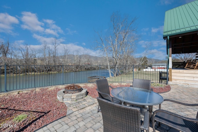 view of patio / terrace featuring an outdoor fire pit, a water view, and fence