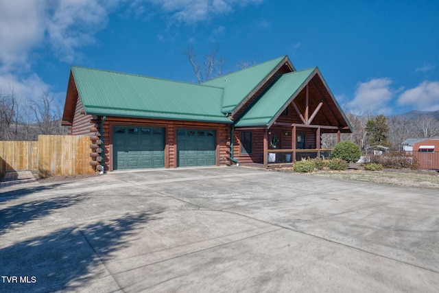 log cabin with a porch, driveway, log exterior, and fence