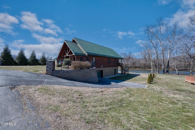 view of home's exterior with metal roof, log exterior, and a yard