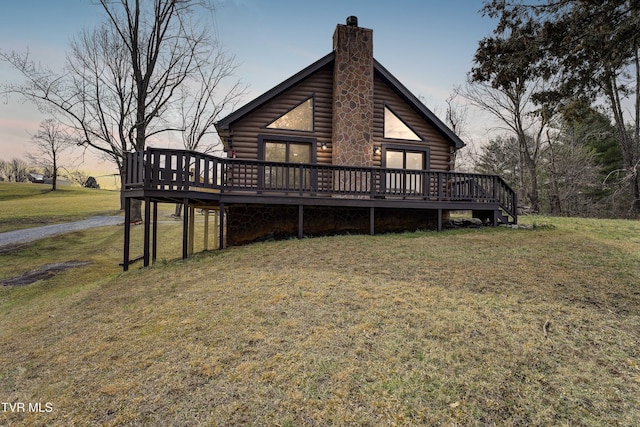 exterior space with a deck, a chimney, log siding, and a lawn