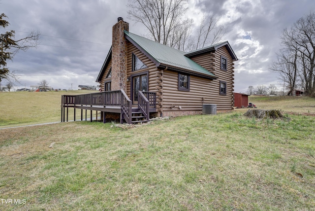 view of property exterior featuring a chimney, a lawn, metal roof, a deck, and log exterior