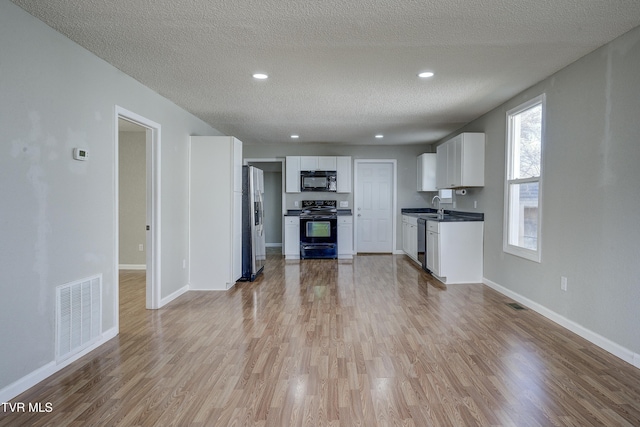 kitchen featuring light wood-style floors, open floor plan, visible vents, and black appliances