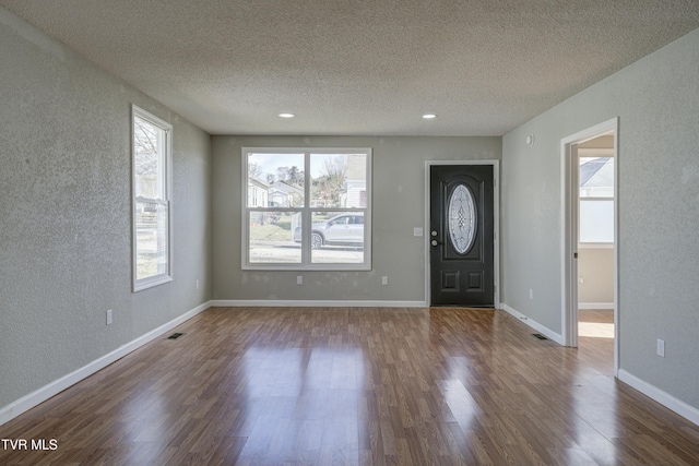 entryway featuring dark wood-style floors, baseboards, visible vents, and a textured ceiling