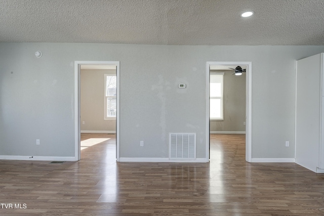 spare room featuring a wealth of natural light, visible vents, baseboards, and wood finished floors