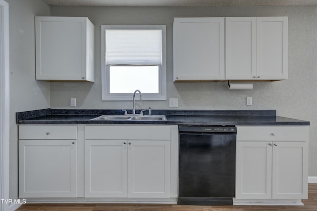 kitchen with dark countertops, black dishwasher, white cabinets, and a sink