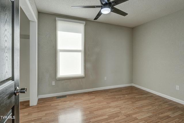 unfurnished room with baseboards, visible vents, a textured ceiling, and light wood finished floors