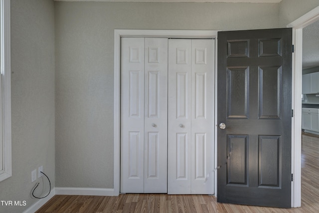 unfurnished bedroom featuring a closet, baseboards, and wood finished floors