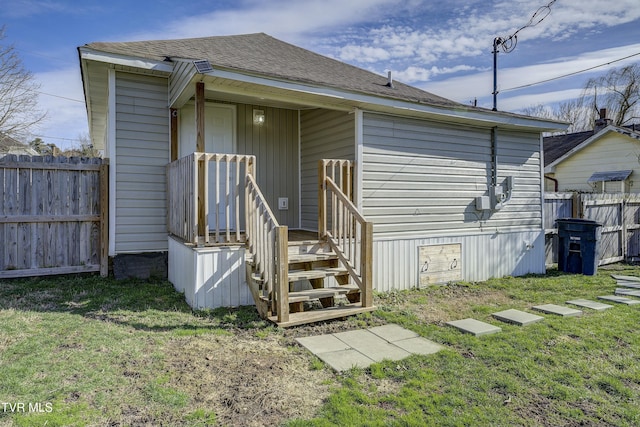 back of property featuring roof with shingles, fence, and a yard