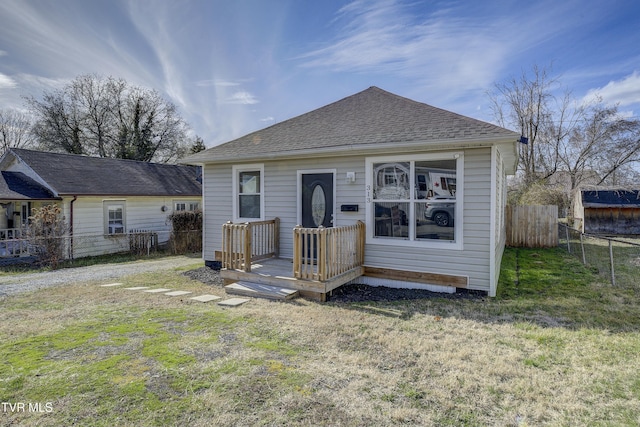 view of front of house featuring a front lawn, a shingled roof, fence, and a wooden deck