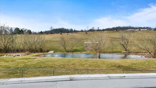 view of swimming pool featuring a water view, fence, and a lawn