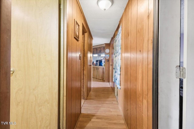 hall featuring wood walls and light wood finished floors