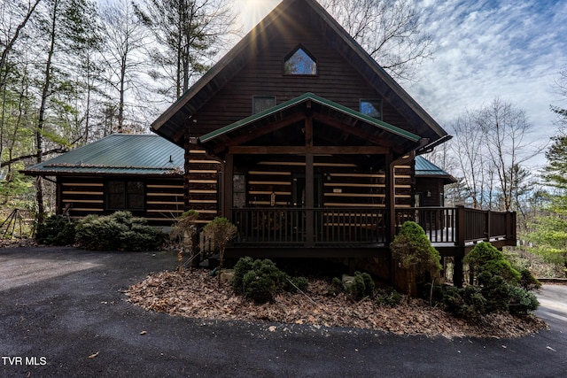 log-style house with metal roof and driveway