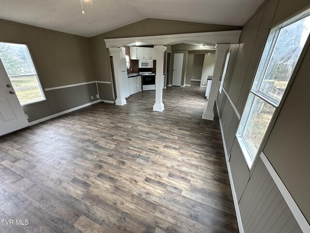 unfurnished living room featuring dark wood-style floors, lofted ceiling, a sink, and ornate columns