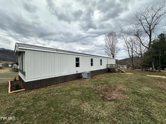 view of side of home with central AC unit, metal roof, and a lawn