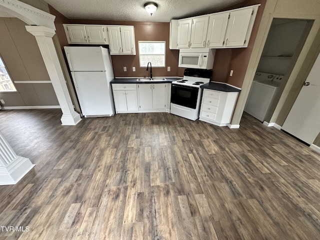 kitchen with dark countertops, a sink, washer / dryer, white appliances, and ornate columns