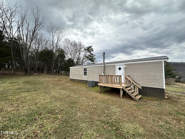 rear view of property featuring a lawn and central air condition unit