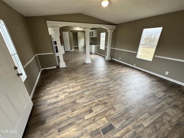 interior space featuring vaulted ceiling, dark wood-style floors, visible vents, and ornate columns