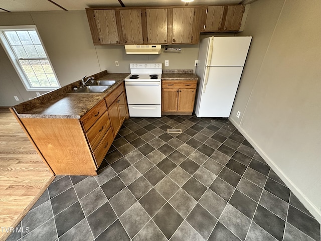 kitchen with under cabinet range hood, a peninsula, white appliances, a sink, and dark countertops