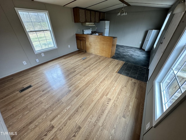 kitchen with lofted ceiling, visible vents, open floor plan, wood finished floors, and white appliances