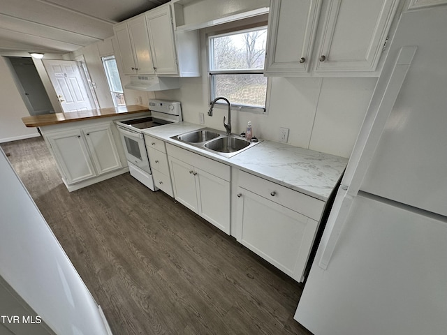 kitchen with a peninsula, white appliances, white cabinets, and a sink