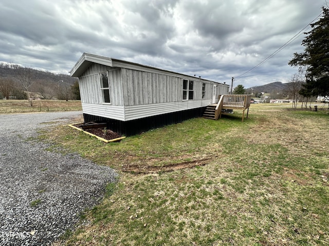 view of property exterior featuring a yard and a deck with mountain view