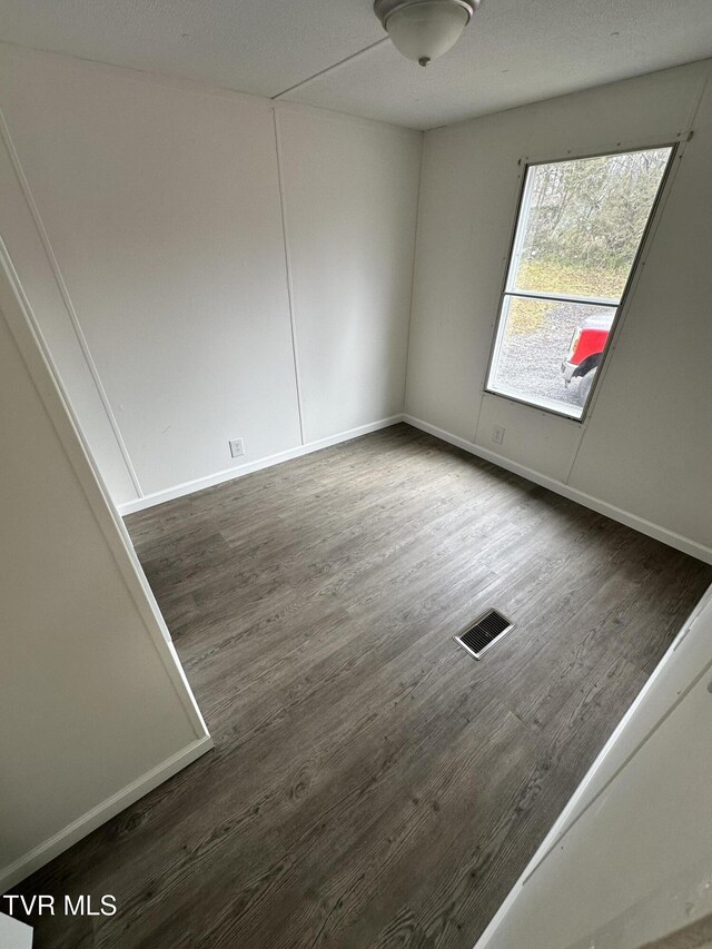 unfurnished room featuring wood finished floors, visible vents, and baseboards