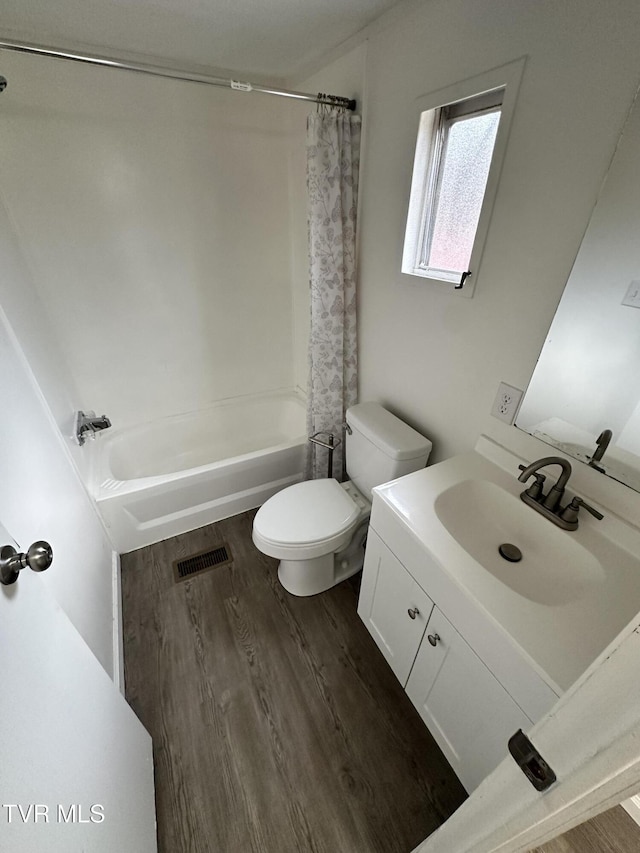 full bathroom featuring toilet, wood finished floors, visible vents, vanity, and shower / bathtub combination with curtain