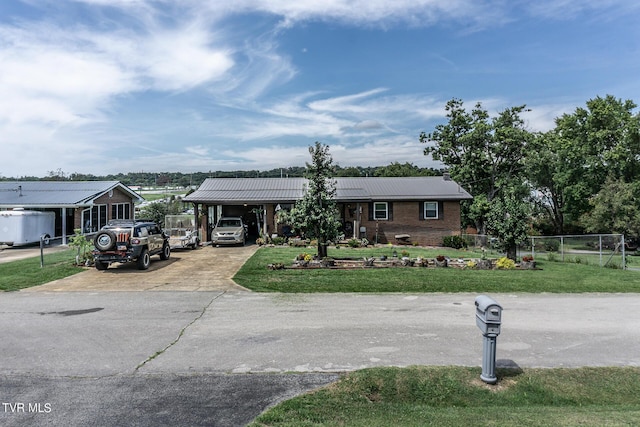 single story home featuring brick siding, concrete driveway, metal roof, fence, and a front lawn