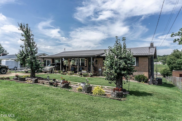 view of front facade with brick siding, metal roof, a standing seam roof, fence, and a front yard