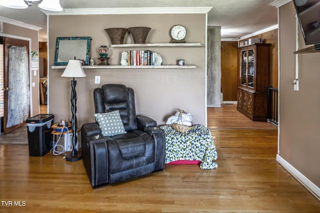 sitting room featuring ornamental molding, baseboards, and wood finished floors