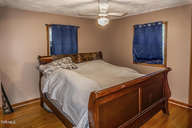 bedroom with ceiling fan, baseboards, and wood finished floors