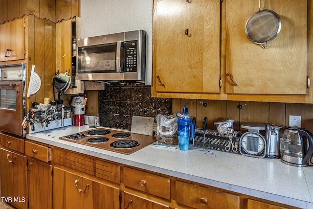 kitchen featuring tasteful backsplash, stainless steel microwave, electric cooktop, and light countertops