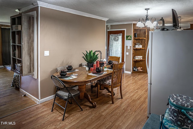 dining space with baseboards, ornamental molding, wood finished floors, a textured ceiling, and a notable chandelier